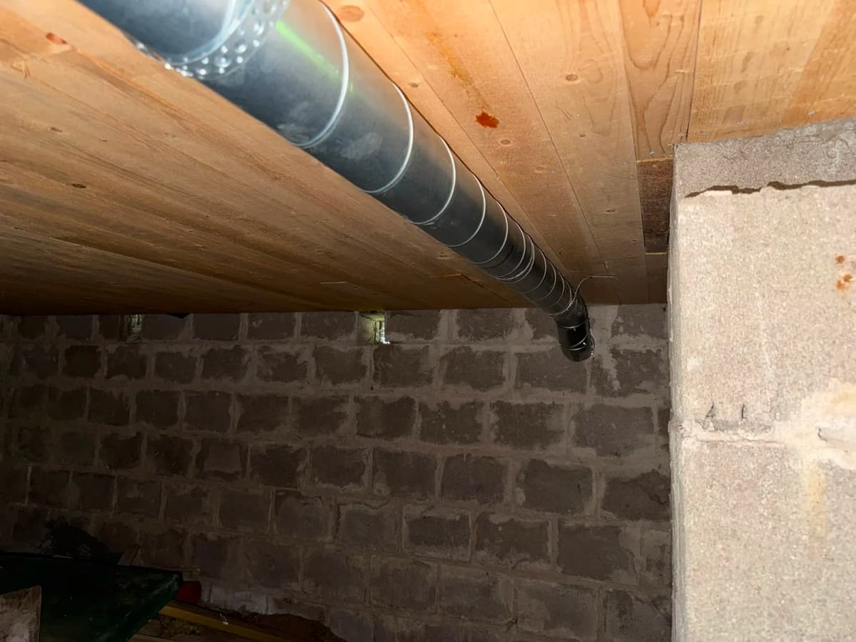 Kanal dras längs träbjälklaget i en källare, utrymmet under huset där radon oftast tar sig in