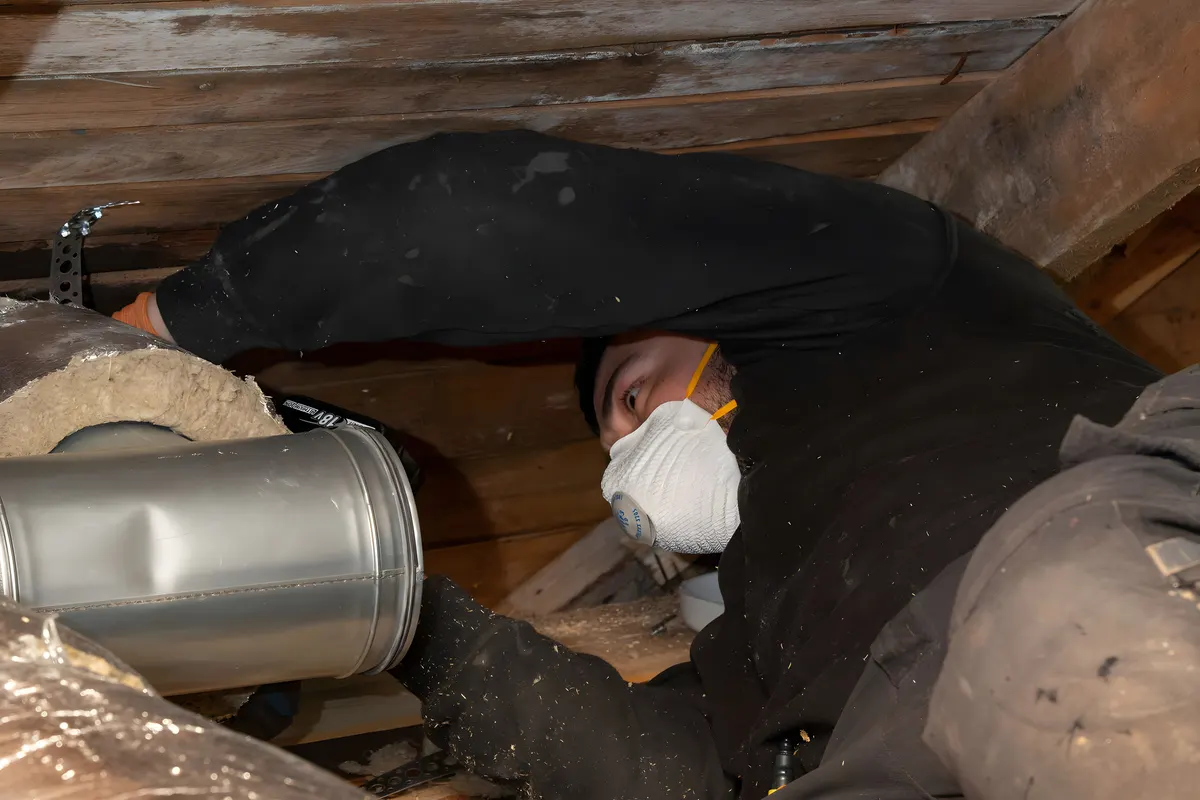Ventilationstekniker med skyddsmask som arbetar vid kanaler inför rengöring i Stockholm